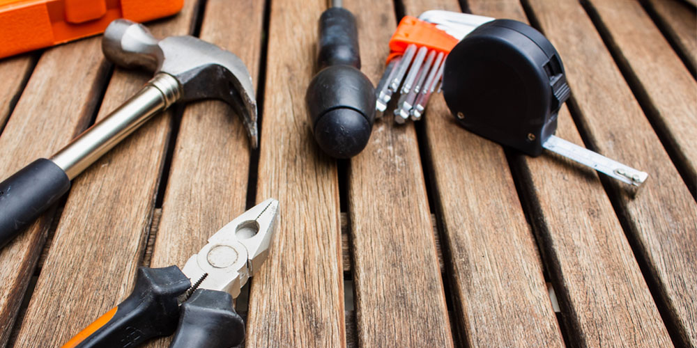 Hand tools including a hammer, tape measure and pliers for a repair job